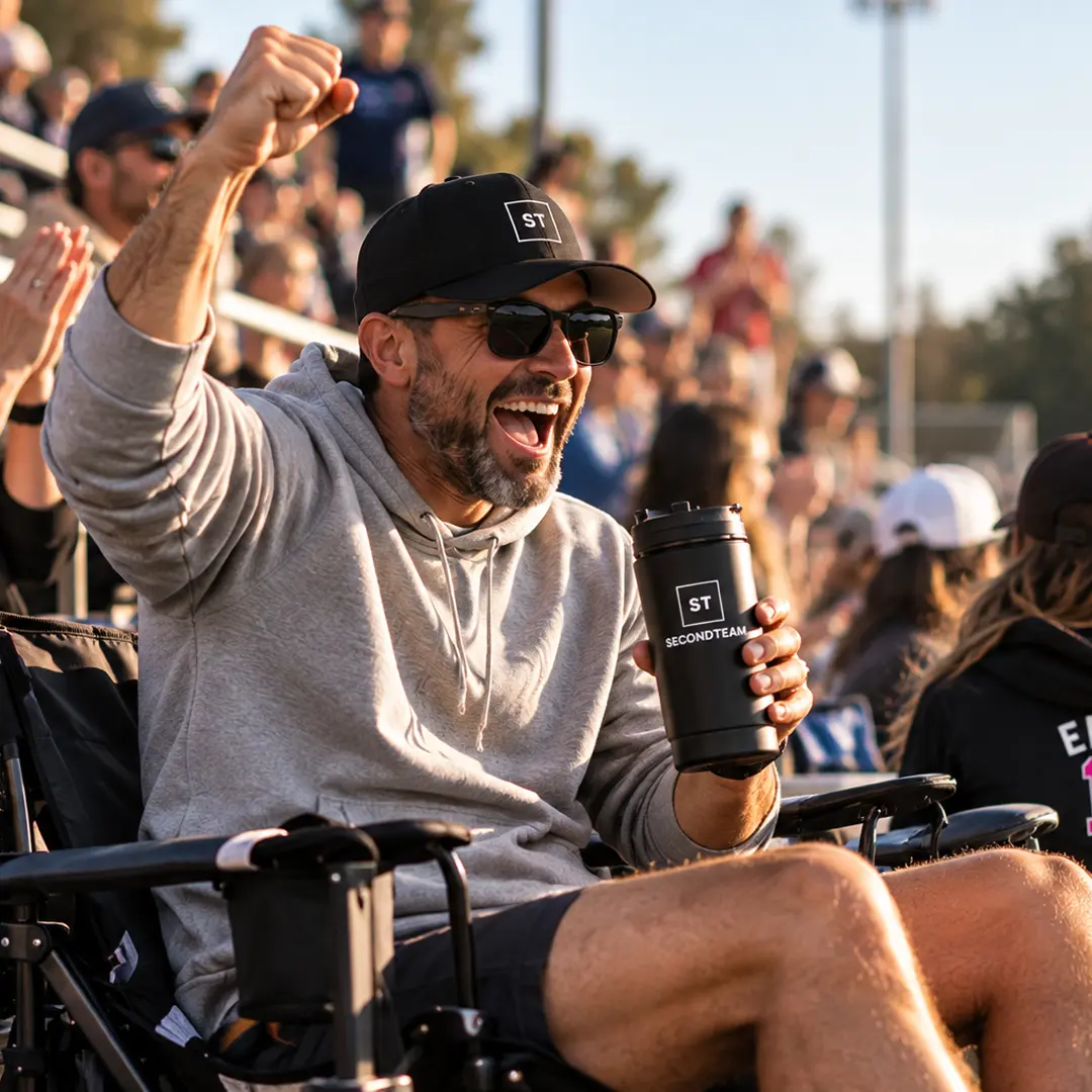 Parent celebrating from the stands with a SECONDTEAM tumbler