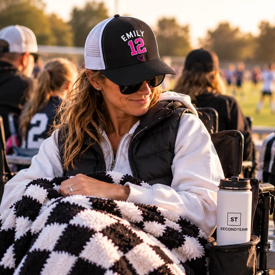 Parent under a blanket in an EMILY 12 cap on the sideline